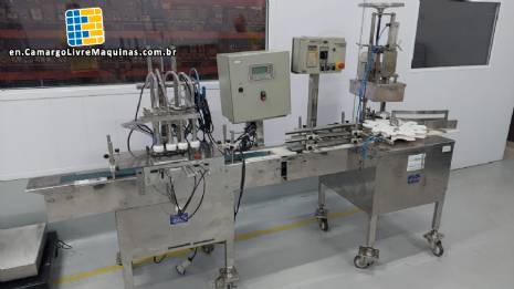 Linear filling machine with 4 stainless steel screw-on nozzles for bottles.