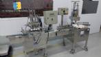 Linear filling machine with 4 stainless steel screw-on nozzles for bottles.